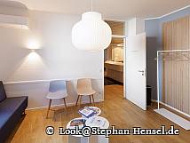 Ansicht des Wartezimmers mit Couch, Stühlen, Gaderobe und Magazinen