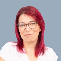 Portrait einer Mitarbeiterin mit roten Haaren und Brille